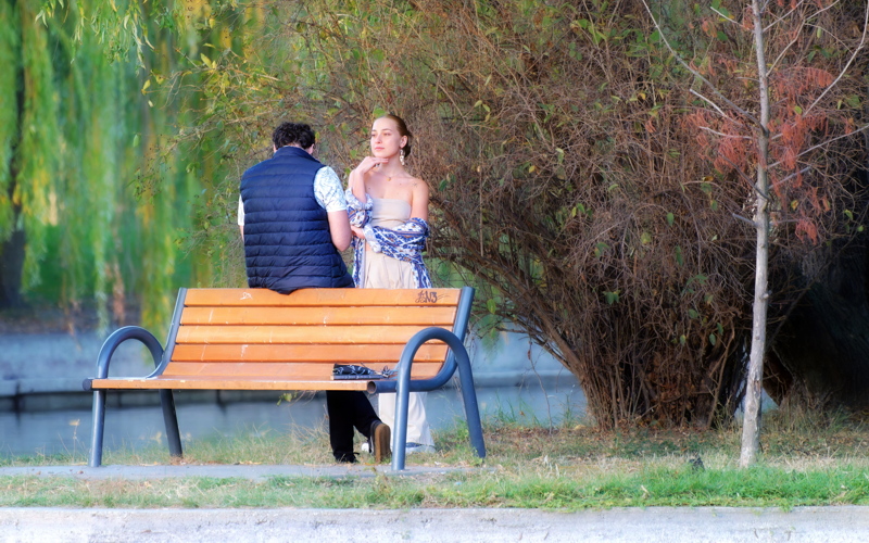 24 - Young couple relaxing by a bench in the park